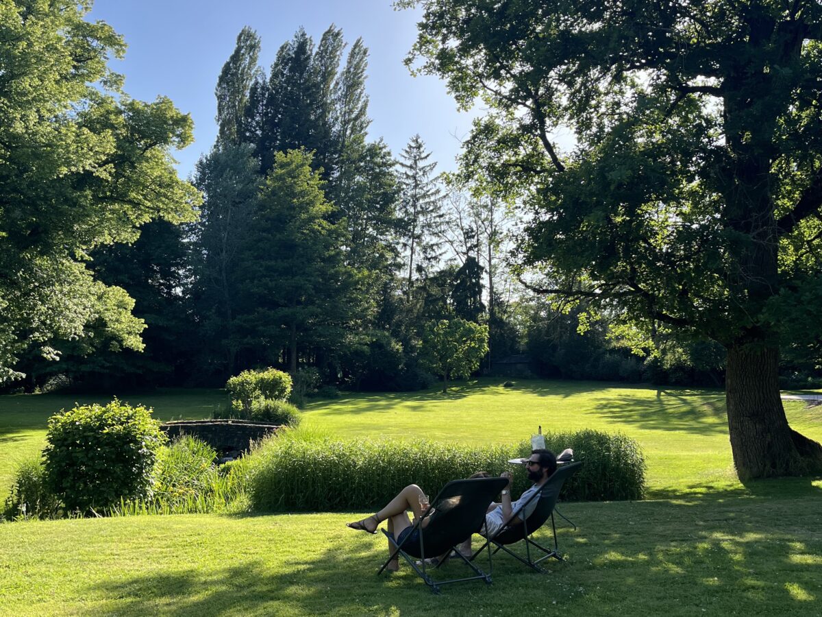 un couple profite d'un apéritif dans des transats au coeur du parc du Moulin de Vilgris, à la lumière du soir.